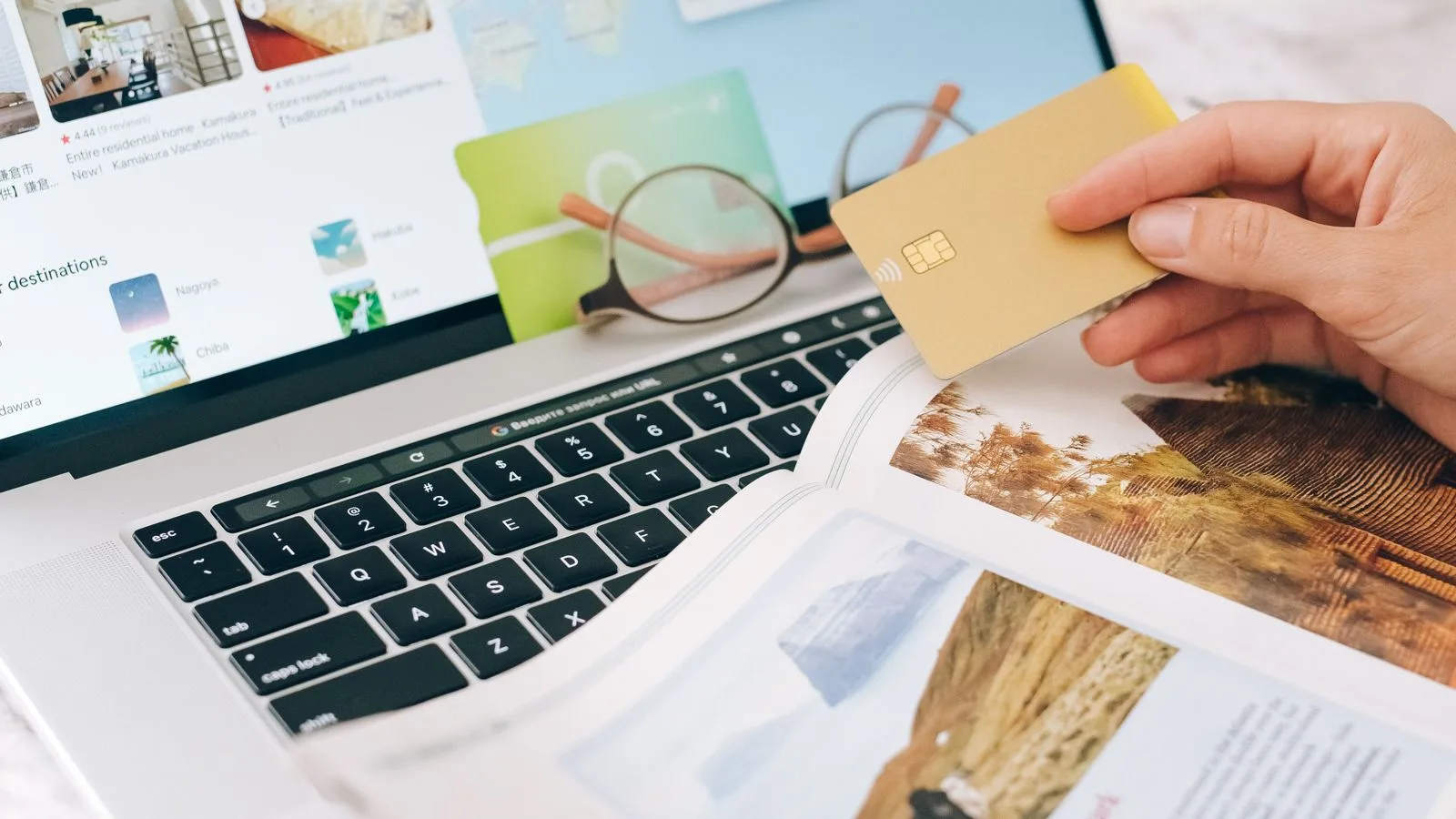 Traveller holding a credit card while booking accommodation on a laptop